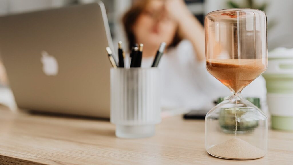 Quanto costa un sito web nel 2024,immagine con clessidra in primo piano, sfondo con computer